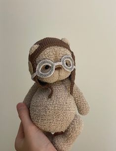 a hand holding a small stuffed animal wearing glasses