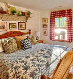 a large bed in a bedroom next to a window with red and white checkered curtains