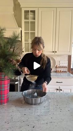 a woman mixing food in a bowl on top of a kitchen counter next to a potted plant