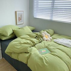 there is a stuffed animal on the green comforter in this bedroom with wood flooring