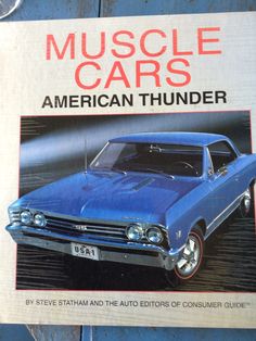 an old blue car sitting on top of a wooden table next to a sign that says muscle cars american thunder