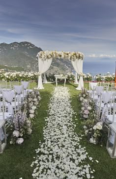 an outdoor wedding setup with white flowers on the aisle