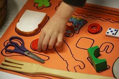 a child's hand on a play mat with scissors and other toys