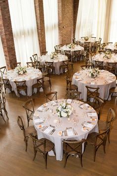 a room filled with lots of tables covered in white tablecloths and centerpieces