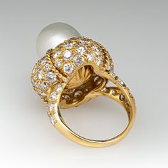 This magnificent cocktail ring is centered with one (1), post set, cultured South Sea pearl. The pearl tops a domed setting is bead set sixty-four (64), bead set, round brilliant cut diamonds. The ring has a split shank design and is accented with seven (7), bead set, round brilliant cut diamonds on each side. The ring measures 21.7mm at the top, rises 18.6mm above the finger, tapering to 2.4mm wide and 1.1mm thick at the base of the shank. The ring is currently size 7. Elegant White Domed Rings, Elegant White Domed Jewelry, Luxury Dome Ring With Cabochon For Wedding, Luxury Oval Pearl Ring, Oval Diamond Pearl Ring For Formal Occasions, Luxury Cabochon Dome Ring For Wedding, Luxury High Luster Pearl Ring For Formal Occasions, Luxury Domed Jewelry For Formal Occasions, Luxury Domed Jewelry For Weddings