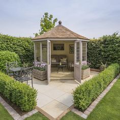 a gazebo in the middle of a garden with tables and chairs