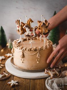 a person is decorating a cake with icing and decorations on the table next to christmas trees