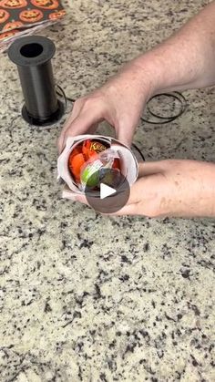 a person holding a cup filled with fruit on top of a counter