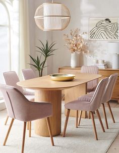 a dining room table with chairs and a bowl on top of it in front of a window