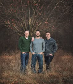 three men standing in front of a tree