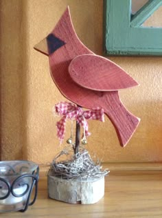 a wooden bird sitting on top of a table next to a pair of eyeglasses