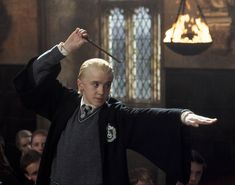 a young boy dressed in harry potter costume holding a wand and pointing to the side