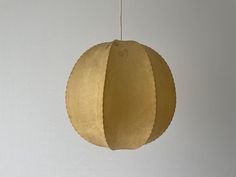 a paper ball hanging from a string on a wall in a room with white walls