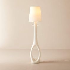 a white table lamp with a light shade on it's side and a cord plugged into the base