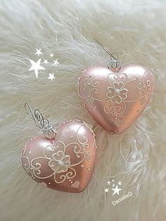 two pink heart shaped ornaments sitting on top of a furry surface