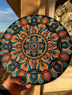 a person holding up a colorful plate with an intricate design on the outside of it