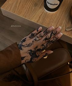 a woman's hand with tattoos on it next to a coffee cup and knife