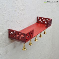 a red shelf with bells hanging from it's sides on a white stucco wall