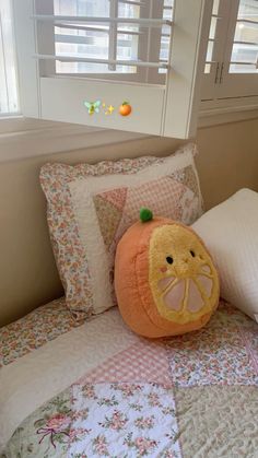 an orange stuffed animal sitting on top of a bed next to pillows and pillow cases