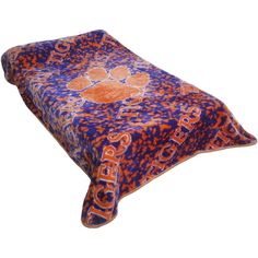 an orange and blue blanket with the clemson logo on it is laying on a white surface