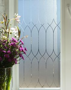 a vase filled with flowers sitting next to a window sill covered in frosted glass