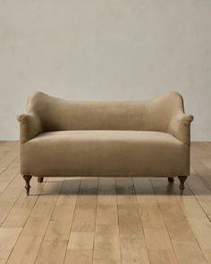 a couch sitting on top of a hard wood floor next to a white wall and wooden floors