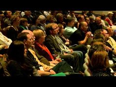 a large group of people sitting next to each other in front of a crowd at a conference