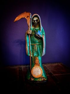 a statue of a person holding a hammer and wearing a green outfit with gold accents