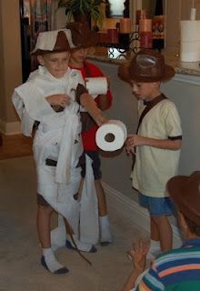 some kids are dressed up in costumes and holding toilet paper while one boy holds a roll of toilet paper