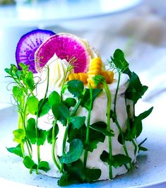 a white plate topped with a cake covered in frosting and veggie toppings