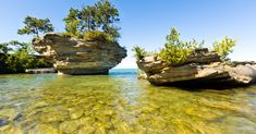 two large rocks sticking out of the water next to each other on a sunny day