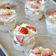 small desserts in plastic cups with strawberries and cream toppings on the top