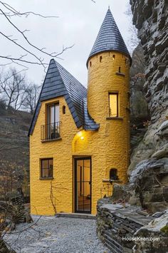 a yellow house with a black roof and two towers on the top of it's side