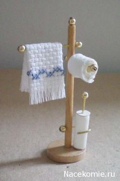 a wooden stand with two rolls of toilet paper on it and a white towel hanging from the top