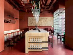 the interior of a restaurant with red walls and wooden tables, wine glasses hanging from the ceiling