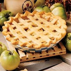 an apple pie sitting on top of a cutting board next to apples and other fruit