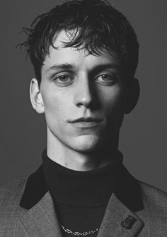 a man in a suit and tie poses for a black and white photo with his eyes wide open