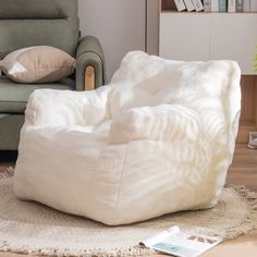 a white bean bag chair sitting on top of a rug in front of a couch