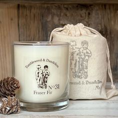 a white candle sitting on top of a table next to a bag and pine cone