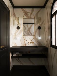 a bathroom with marble walls and black counter tops, along with a mirror on the wall