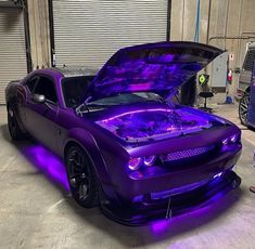 a purple sports car with its hood up and lights on it's engine bay