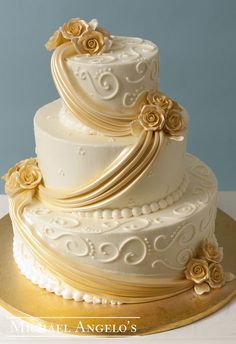 a three tiered white wedding cake with gold flowers