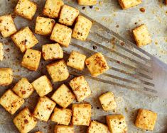 tofu cubes on a baking sheet with a spatula next to them and seasoning