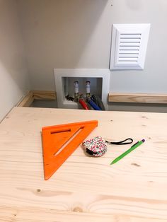 an orange triangle shaped object sitting on top of a wooden table next to some scissors