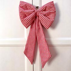 a red and white gingham bow hanging on the front door to give it an elegant touch