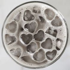 a glass filled with liquid and lots of heart shaped bubbles in it's bottom