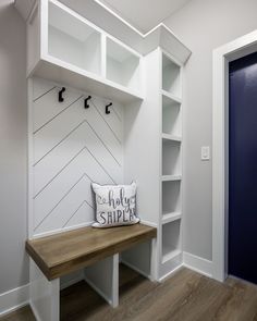 a bench with a pillow on it in front of a white bookcase and blue door