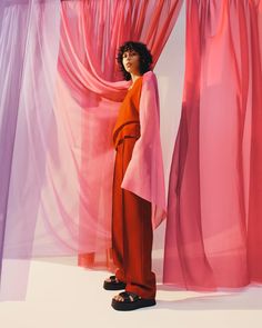 a woman standing in front of pink curtains