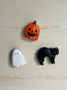 three halloween decorations on a table with one black cat and the other white ghost face