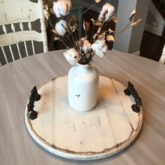 a white vase filled with flowers on top of a wooden table